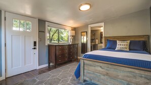 A bedroom with a wooden bed, a dresser, a window, and a door. - Waterfront Lake LBJ Cabin w/ Private Dock! (Burnet)