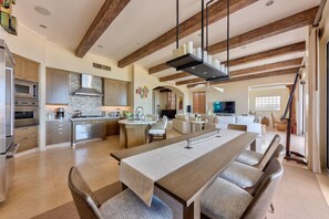 Enjoy a spacious open-plan kitchen with a central island, dining area, and cozy seating area with a sofa and flat-screen TV.