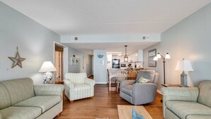 A living room with two sofas, a coffee table, and a dining area with chairs and a table.