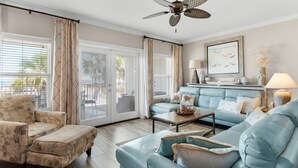 Ein Wohnzimmer mit Sofa, Sessel und Deckenventilator.