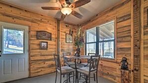 A wooden interior with a dining table, chairs, a ceiling fan, and a window with blinds. - 'Sardis Serenity' 1 BR Clayton Cabin w/ Lake View (Clayton)