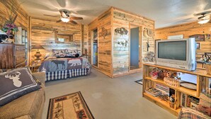 A rustic cabin interior with a bed, television, and wooden shelves. - 'Sardis Serenity' 1 BR Clayton Cabin w/ Lake View (Clayton)