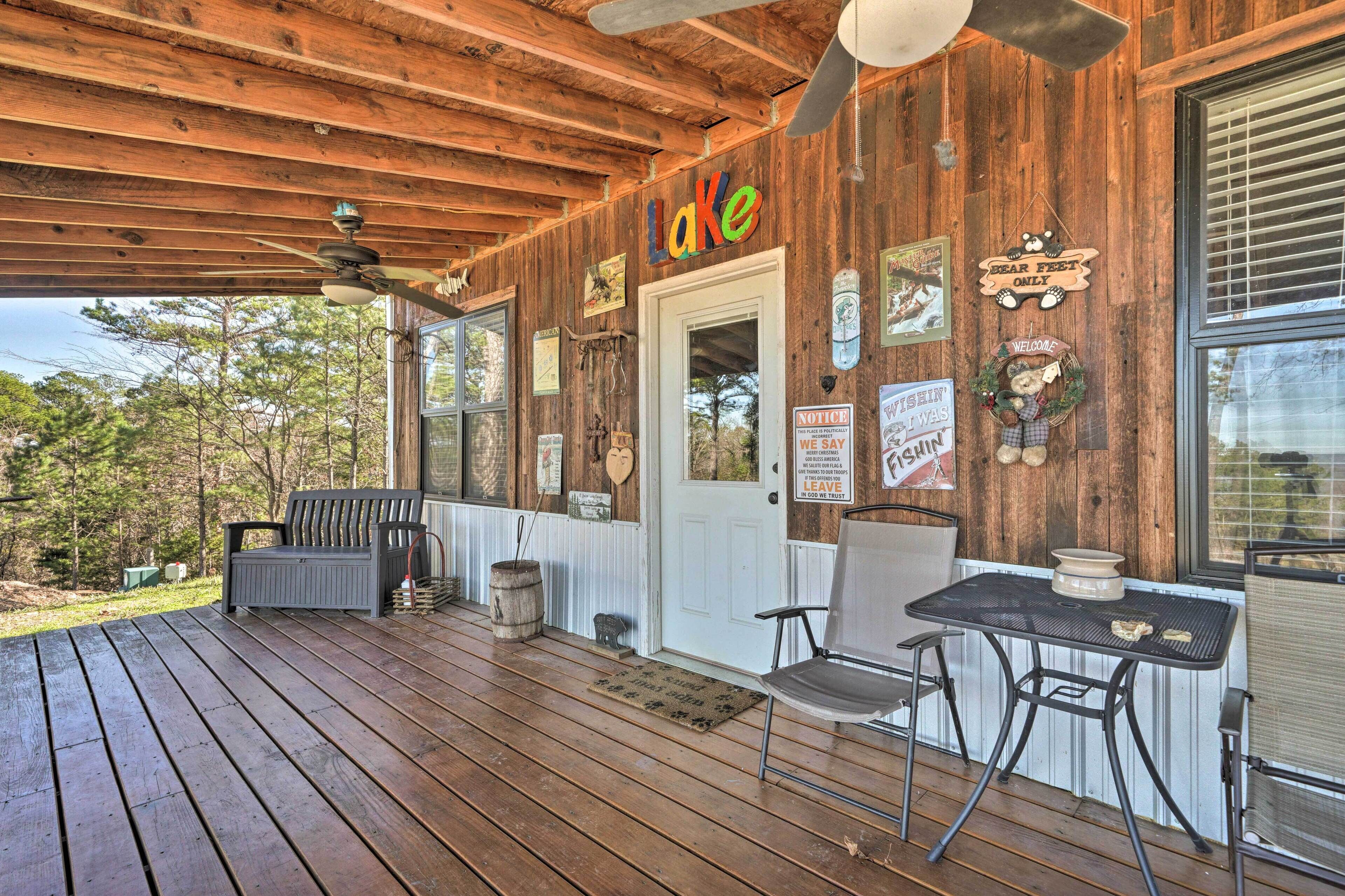 Une terrasse en bois avec un ventilateur de plafond, un banc et une table avec des chaises.