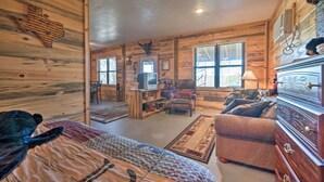 A log cabin-style room with a bed, a dresser, a television, and a fireplace. - 'Sardis Serenity' 1 BR Clayton Cabin w/ Lake View (Clayton)