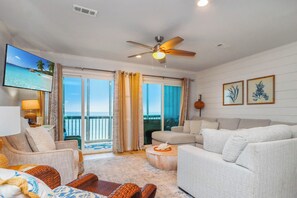 A hotel room with a balcony, a ceiling fan, a flat-screen TV, and a sofa. - On Top Of The Beach, Screen Porch, Gulf & Bay Views ~ Their Inheritance (Cape San Blas)