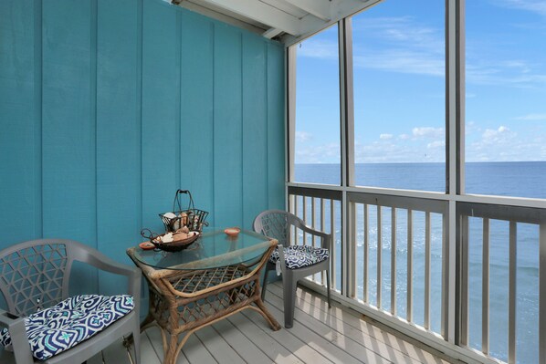 A balcony with a glass table and wicker chairs, overlooking the sea. - On Top Of The Beach, Screen Porch, Gulf & Bay Views ~ Their Inheritance (Cape San Blas)
