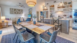 Una cocina moderna con una isla central, electrodomésticos de acero inoxidable y un comedor con mesa y sillas de madera.