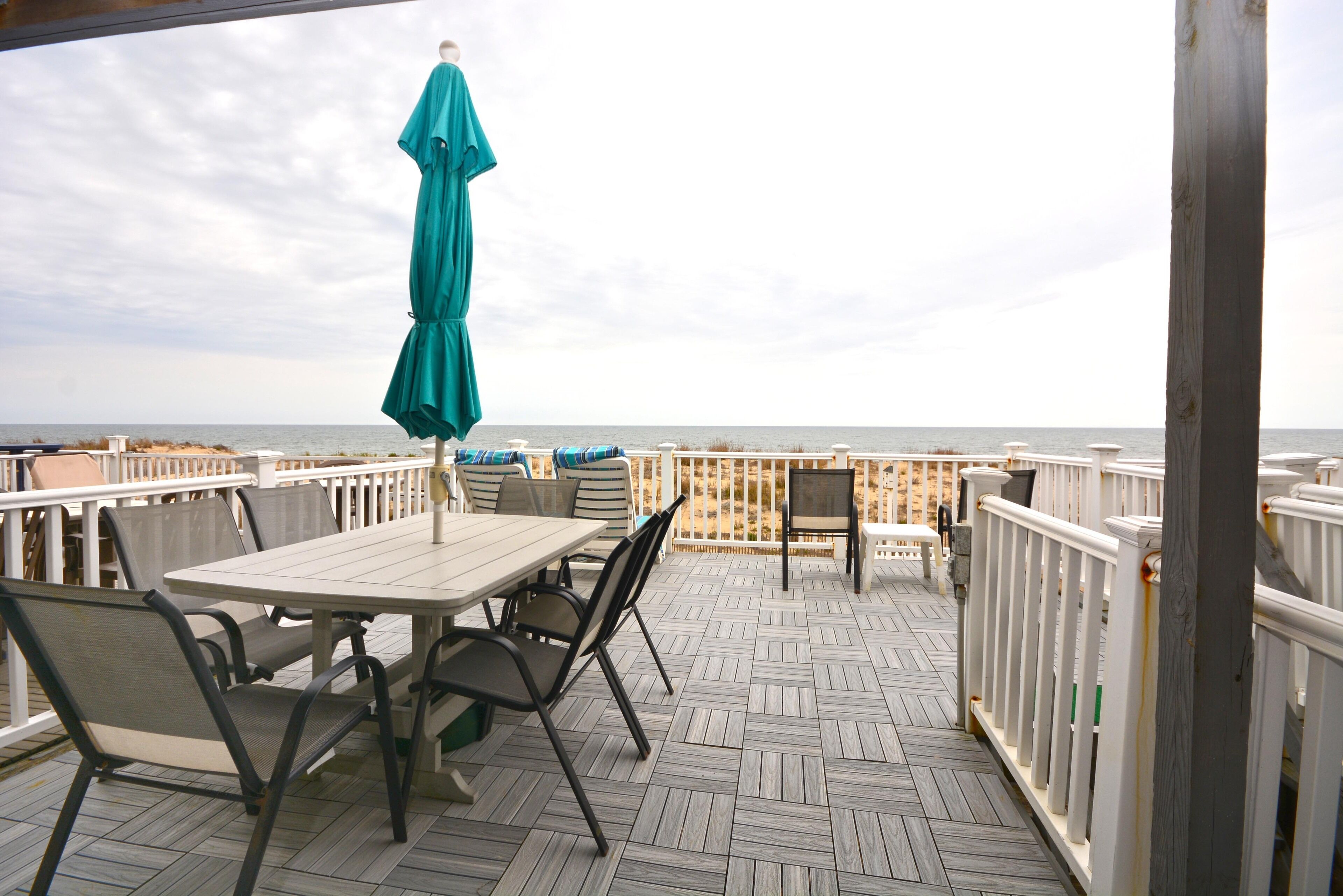 Una terraza de madera con una mesa y sillas, con vista al mar.