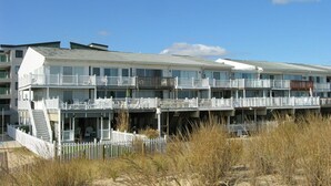 Un hotel sulla spiaggia con numerosi balconi, una zona esterna coperta e uno sfondo sabbioso.