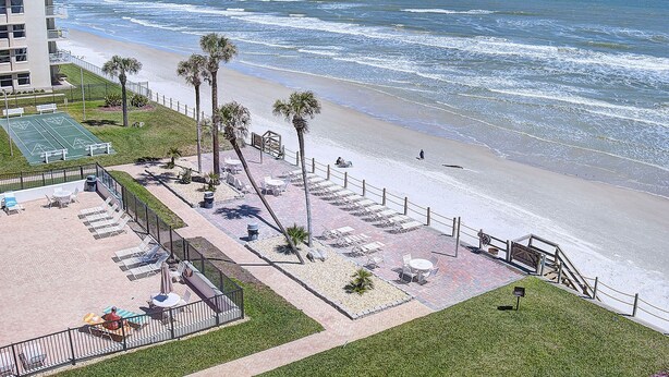Hotel a primera línia de platja amb zona de terrassa, palmeres i vista a l'oceà.