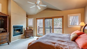 Une chambre dotée d’un grand lit, d’une cheminée, d’un ventilateur de plafond et offrant une vue sur l’extérieur grâce à une porte coulissante.
