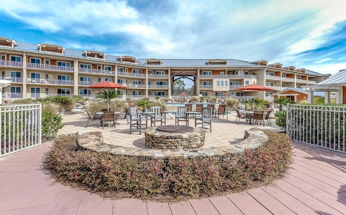 A courtyard with outdoor seating, a central fire pit, and a multi-story building with balconies.