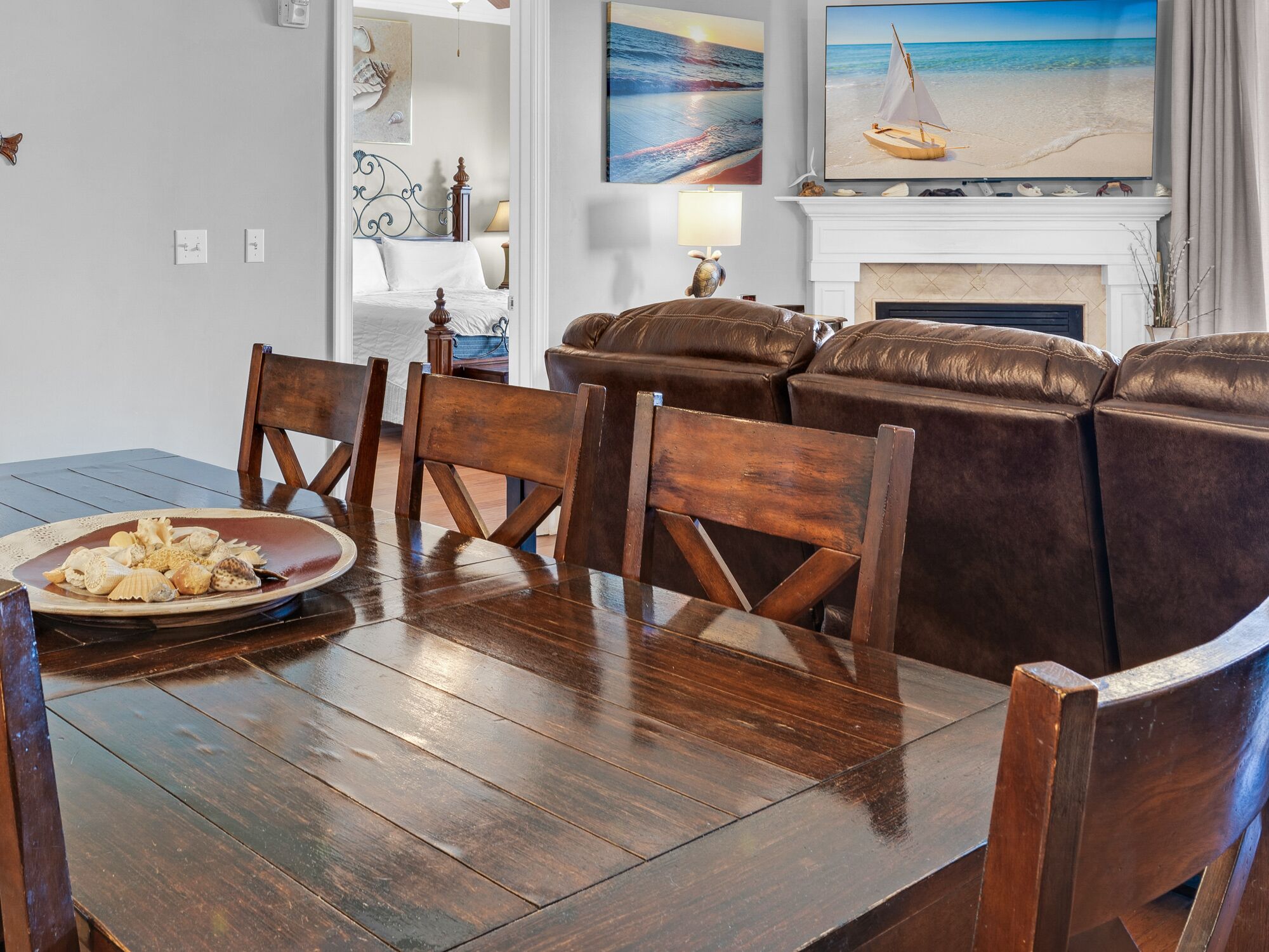 A dining area with a wooden table, chairs, and a decorative plate of seashells.