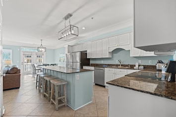 Fully equipped coastal kitchen with breakfast bar seating and modern appliances—ideal for family meals after the beach.