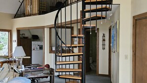 Uma sala de estar espaçosa com escada em espiral, uma mesa de jantar e um sofá.