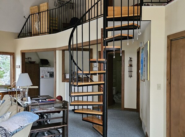 A spacious living area with a spiral staircase, a dining table, and a sofa.