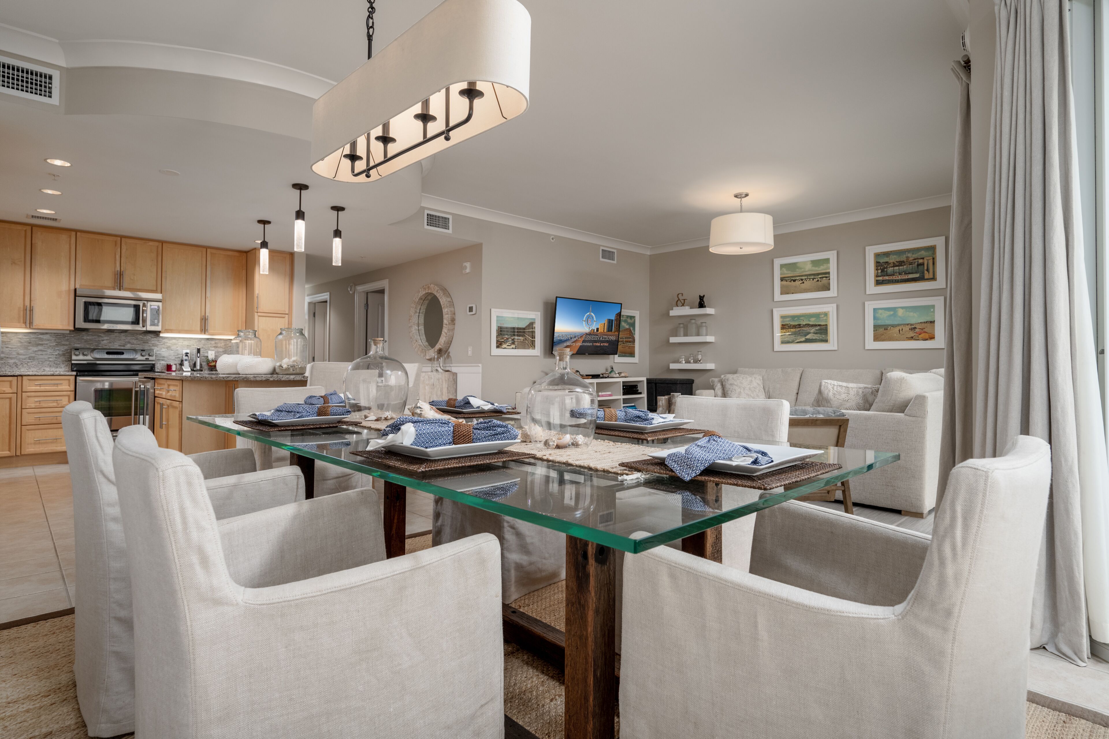 A modern kitchen with a microwave, oven, and stainless steel appliances. There is a dining area with a glass table and white chairs.