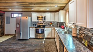 A modern kitchen with white cabinets, stainless steel appliances, a wooden ceiling, and a granite countertop. - Lovely Livingston Loft w/ Mountain & River Views! (Livingston)