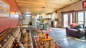 A spacious living area with a wooden ceiling, a sofa, a coffee table, and a dining table with chairs. - Lovely Livingston Loft w/ Mountain & River Views! (Livingston)