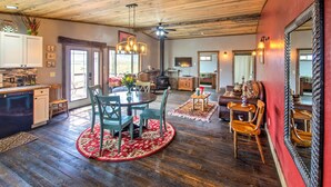 A spacious living area with a wooden ceiling, a dining table with chairs, a fireplace, and a large mirror. - Lovely Livingston Loft w/ Mountain & River Views! (Livingston)