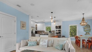A living room with a sofa, coffee table, and a view into the kitchen. - 0.2 Mi to Beach, Tiki Bar, Huge Pool, Close to Silver Sands Shopping (Miramar Beach)