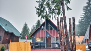 A cabin with a red and black exterior, a wooden deck, and a view of surrounding trees. - Inviting Mt Hood Cabin w/ Porch: 1 Mi to Skibowl! (Government Camp)