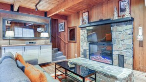 A cozy living room with a stone fireplace, wooden ceiling, and a modern sofa. - Inviting Mt Hood Cabin w/ Porch: 1 Mi to Skibowl! (Government Camp)