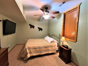 A bedroom with a bed, a ceiling fan, a mounted TV, and a window with blinds. - Berry Bear Depot @ Spring Brook Resort (Wisconsin Dells)