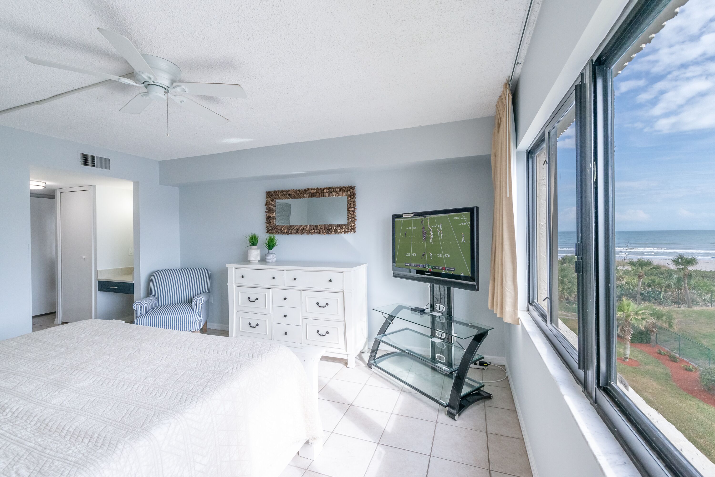 A bedroom with a bed, a dresser, a television, and a window with a view.