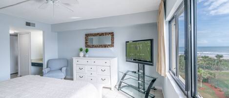 A bedroom with a bed, a dresser, a television, and a window with a view.