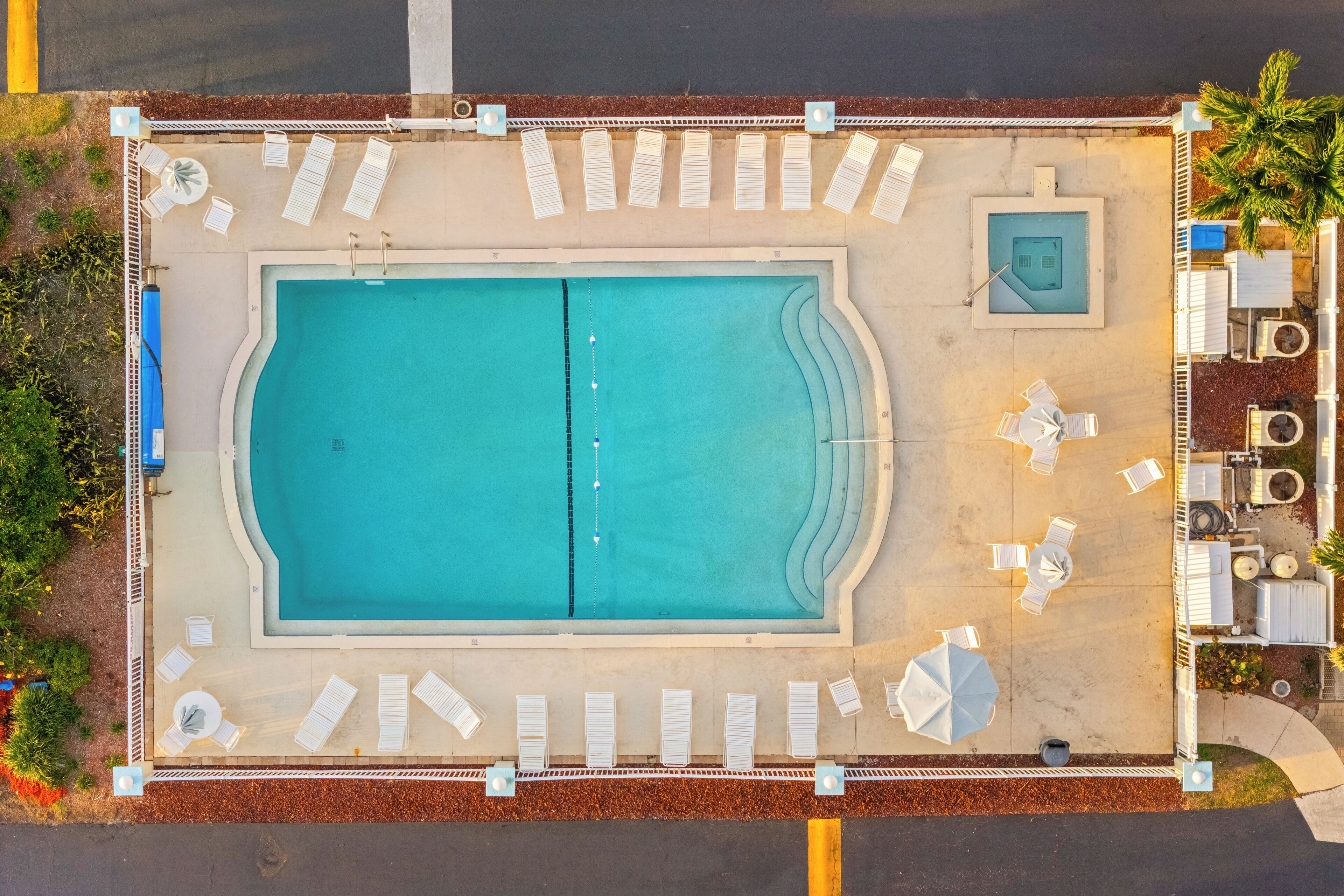 Vista aérea de una piscina con tumbonas y una pequeña zona de hidromasaje.