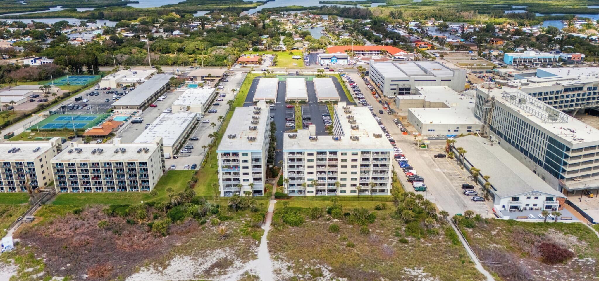 An aerial view of a hotel complex with multiple buildings, parking areas, and a construction site.