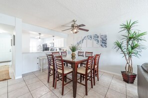 Un coin repas avec une table et des chaises en bois, un ventilateur de plafond et une plante en pot.