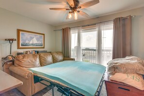 A bedroom with a bed, a desk, a chair, a ceiling fan, a window with curtains, and a painting on the wall. - Family Beach Retreat w/ Pool & Views in Galveston (Galveston)