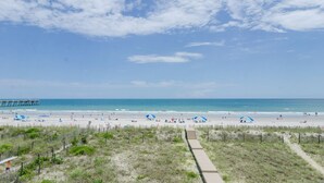 A beach with a pier, sandy shore, and a clear sky.