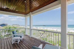 A wooden deck with white railings overlooking a beach and pier. - Grand 5BR oceanfront home w private beach access! (Wrightsville Beach)
