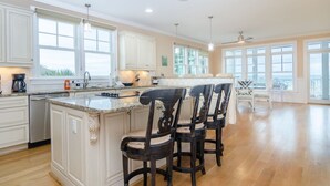 A spacious kitchen with a large island, white cabinetry, and a view of the outdoors.