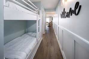 A narrow hallway with bunk beds on one side and a 'welcome' sign on the wall. - GD 307: Seaglass Cove - Step Out, Chill Out... Beachfront Living at Its Best! (Fort Walton Beach)
