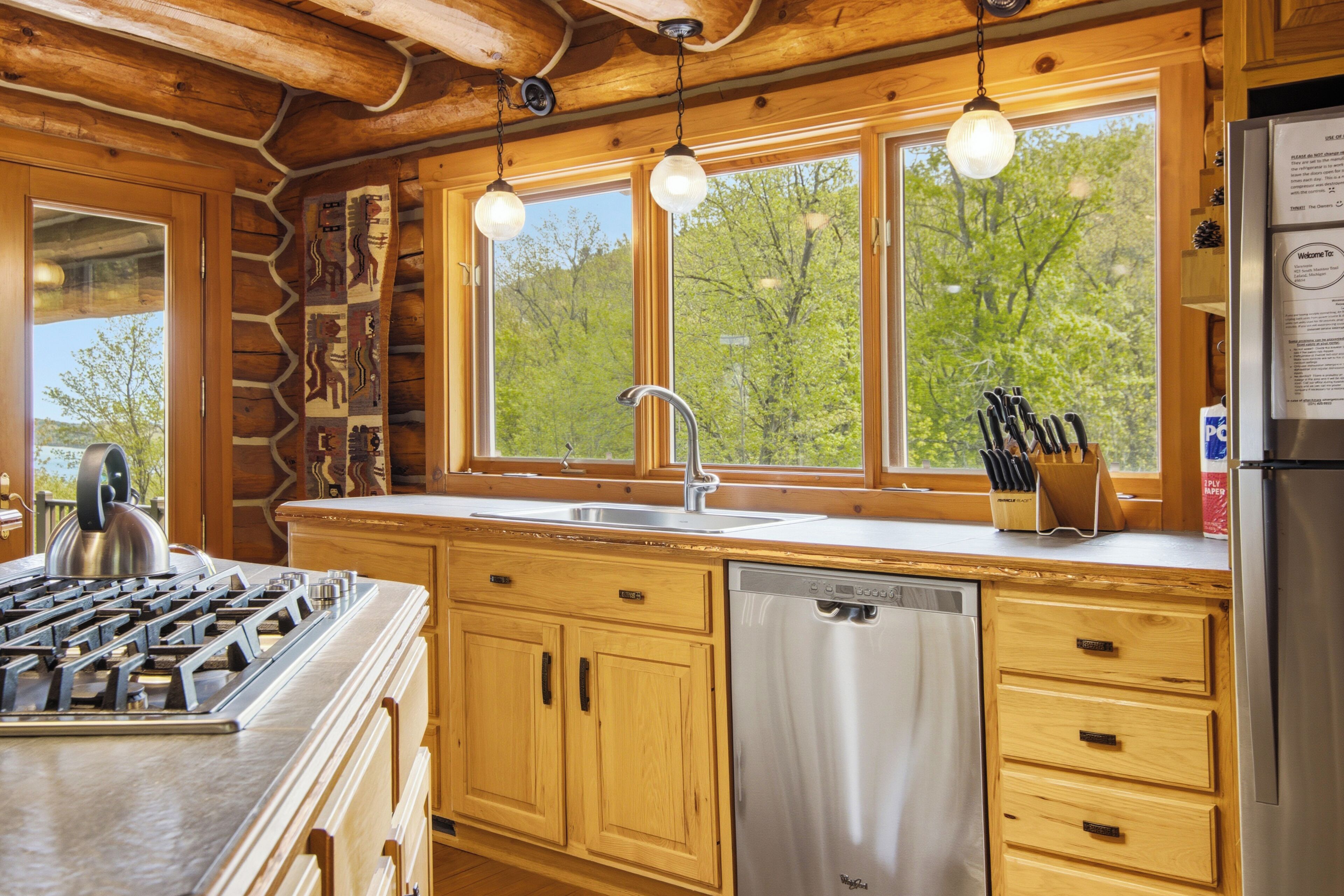 A cabin-style kitchen with wooden cabinetry, a stainless steel dishwasher, and a gas stove.
