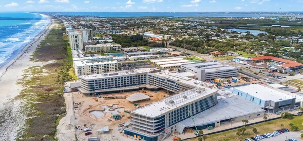 A coastal urban area with a beachfront, multi-story buildings, and a large parking lot. - Cocoa Beach Paradise: Oceanview Condo w/ Heated Pool & Spa-Like Hot Tub🌴 (Cocoa Beach)