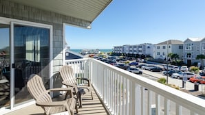 Ein Balkon mit zwei Adirondack-Stühlen, Blick auf einen Parkplatz und Gebäude im Hintergrund.