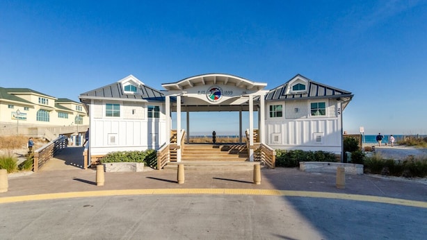 Ein Gebäude direkt am Strand mit überdachter Veranda, einer Uhr und Blick auf das Meer.