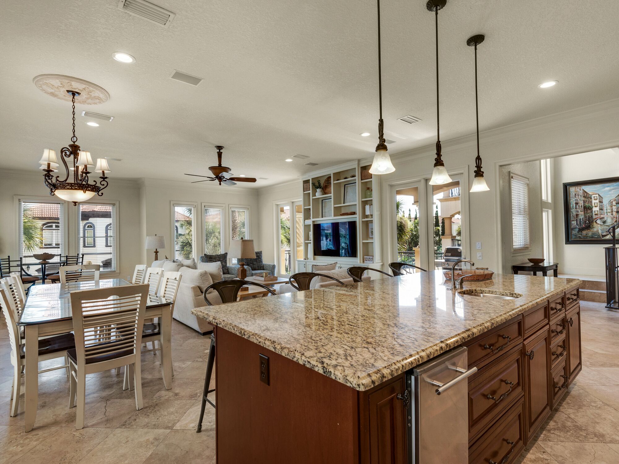A spacious kitchen with granite countertops, wooden cabinets, and pendant lighting.