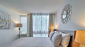 Een slaapkamer met een groot bed, een spiegel en een raam met gordijnen.