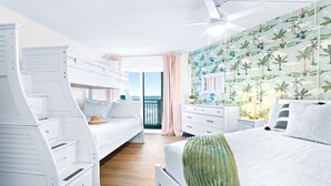 Ein Schlafzimmer mit einem Etagenbett, einem Einzelbett, einem Schminktisch, einem Nachttisch und Meerblick.