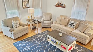 Ein Wohnzimmer mit einer Couch, einem Sessel, einem Couchtisch und einem Teppich.