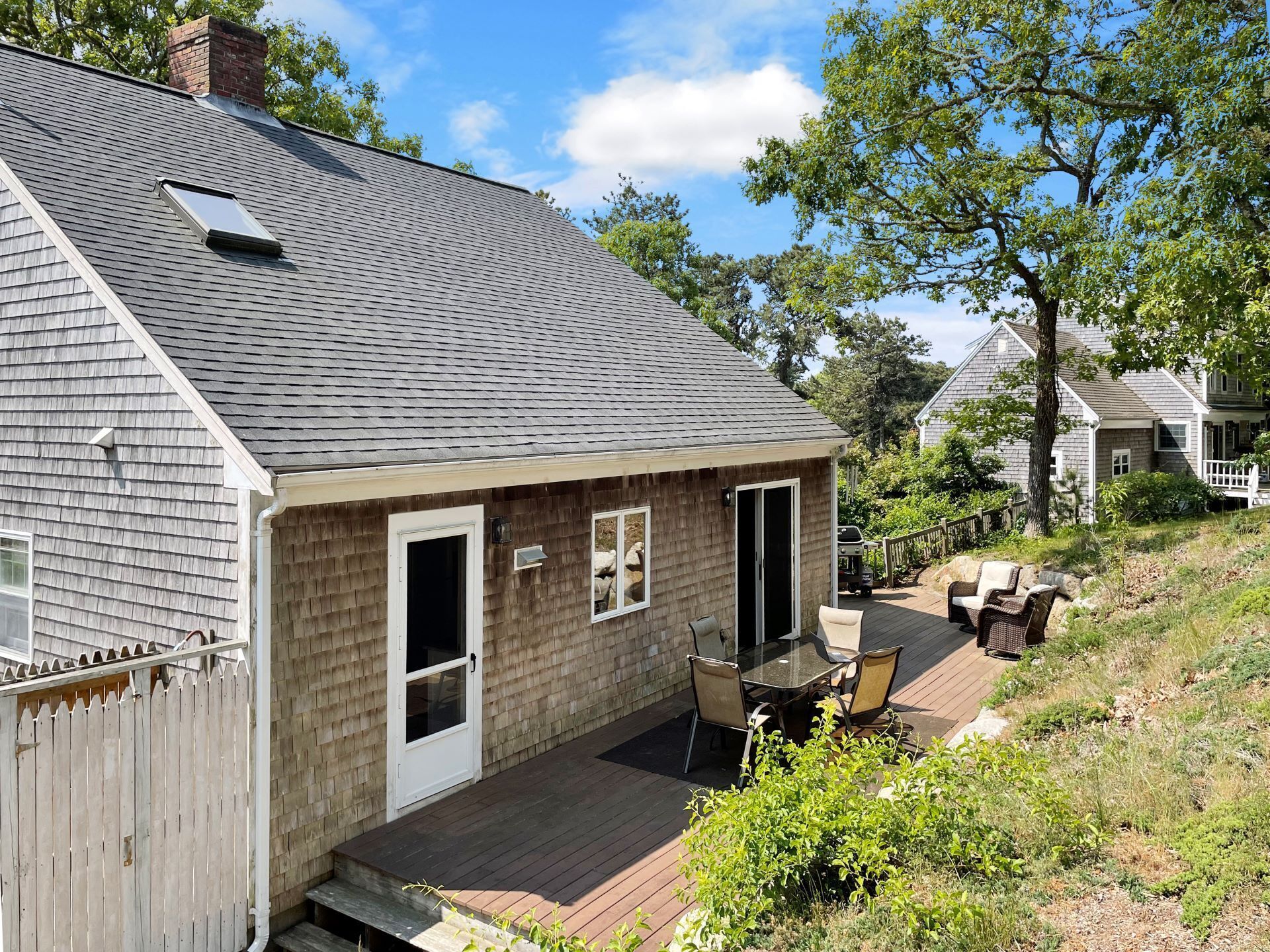 A single-story house with a deck, a small attached garage, and a chimney.