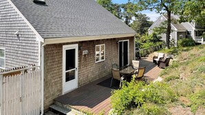 Ein eingeschossiges Haus mit einer Terrasse, einer kleinen angebauten Garage und einem Schornstein.
