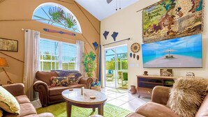 A living room with a sofa, armchairs, a coffee table, and a television. - Near Disney Parks 10 min. Themed rooms, game room, Private Pool with Screen deck (Kissimmee)