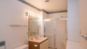 A bathroom with a toilet, sink, mirror, and shower.